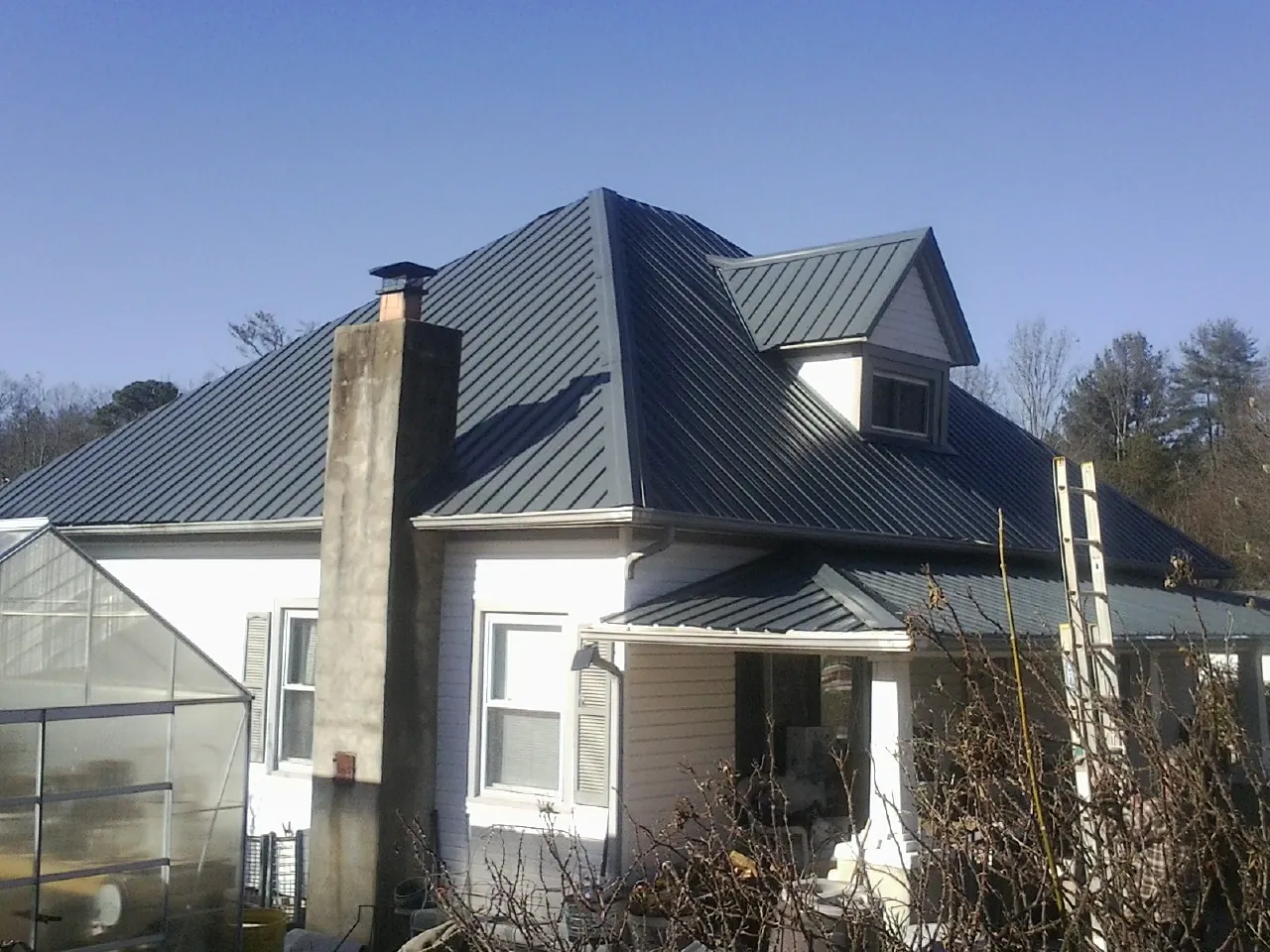 Dark blue standing seam metal roof on a white farmhouse with dormer — Slate & Tile Roof Repair by Roofing Brothers in Marshallville