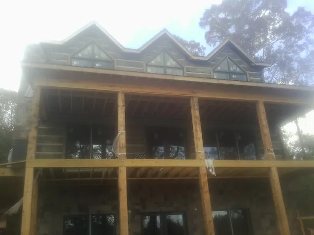 Dormers and porch framing on a large log home under construction — Roof Coating work by our crew in Marshallville