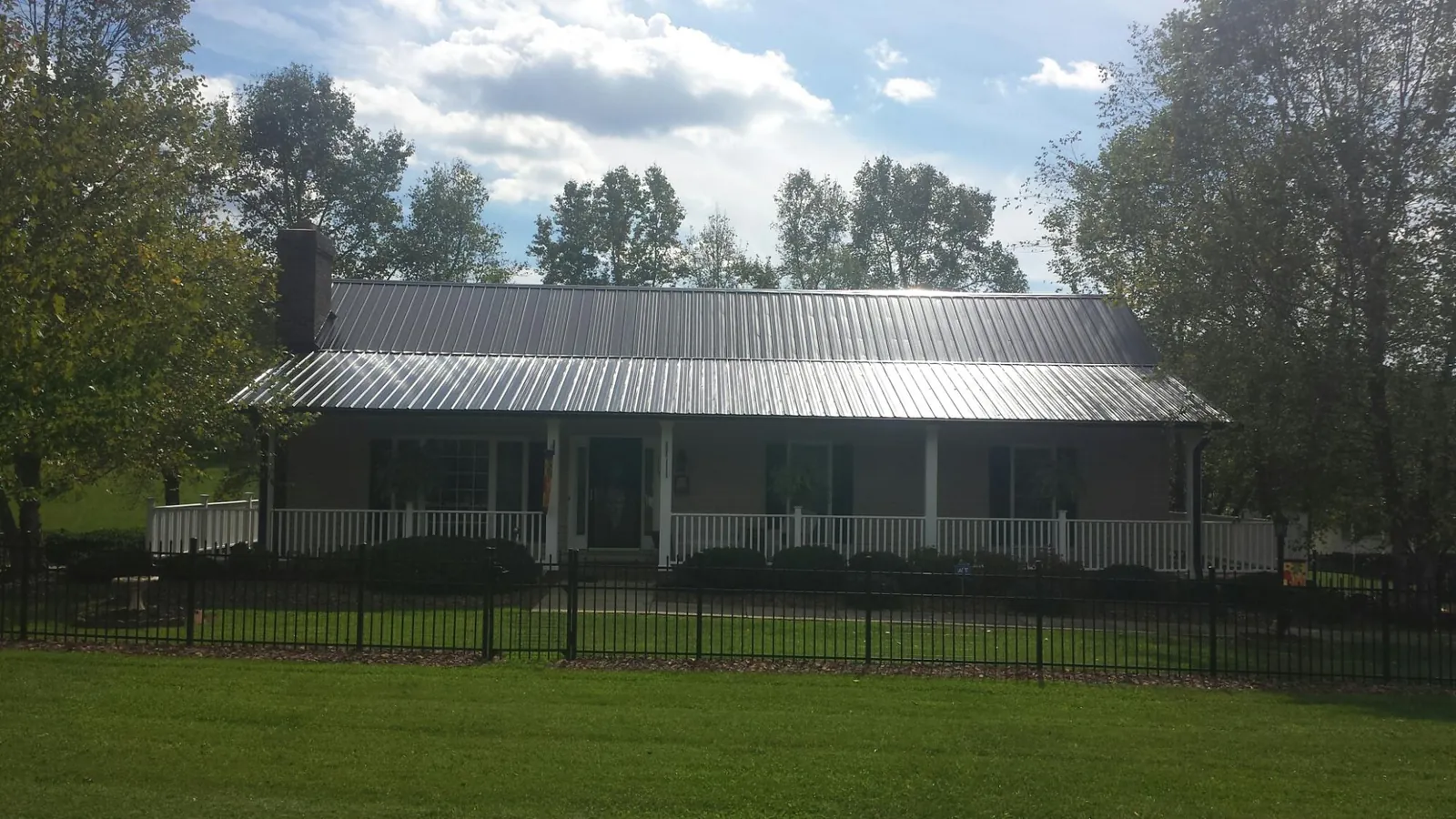 Gray metal roof on a brick ranch with a full width front porch — Gutter Guard Installation work by our crew in Marshallville