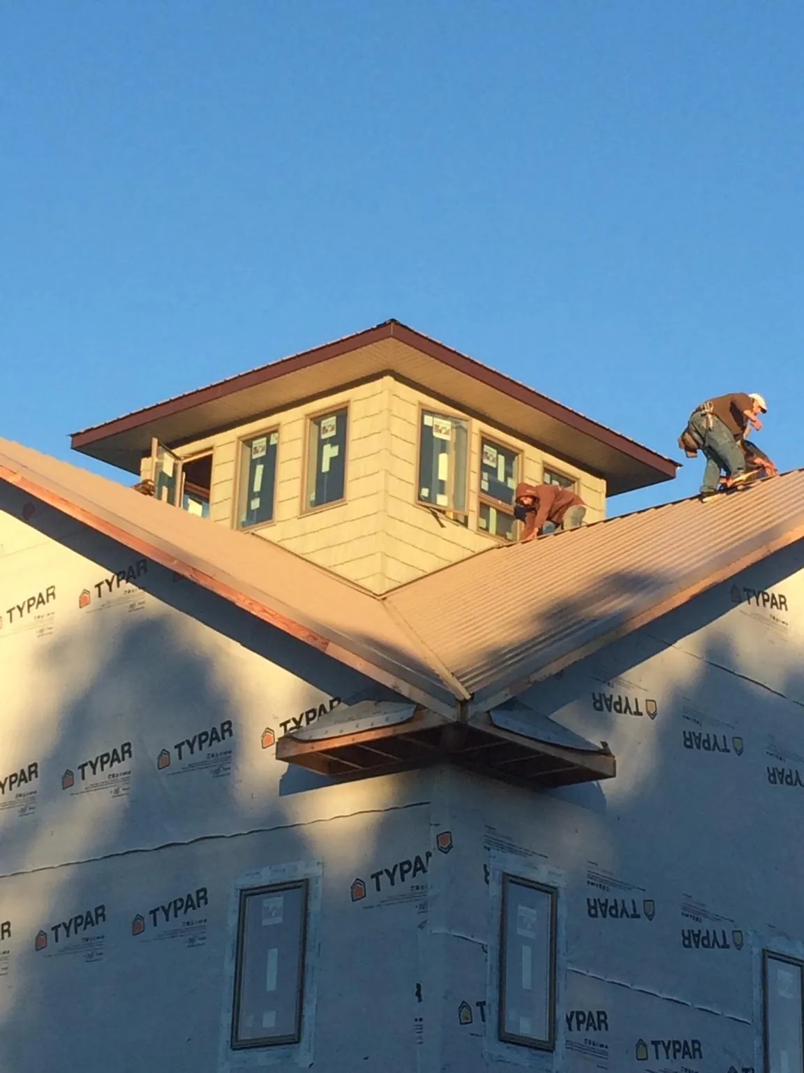 Roofers working around a rooftop cupola on a new metal roof at sunset — Roof Waterproofing in Marshallville by Roofing Brothers